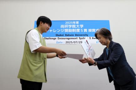 鈴木学長から賞状を受け取る学生