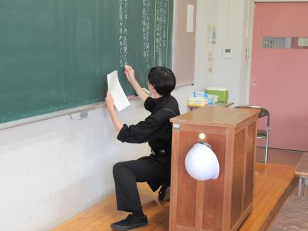 生徒役の学生が見やすいよう、しゃがんで書いています。